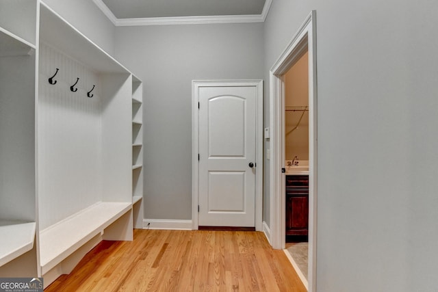 mudroom featuring crown molding, a sink, baseboards, and light wood-type flooring