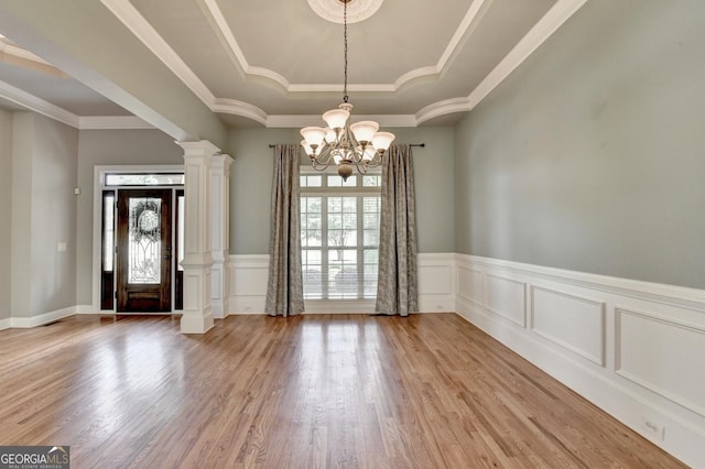 interior space with plenty of natural light, a raised ceiling, wood finished floors, and a notable chandelier