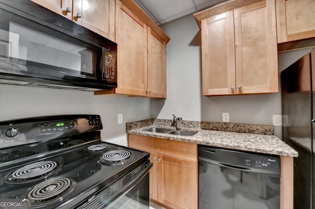 kitchen featuring light stone counters, a sink, light brown cabinetry, and black appliances