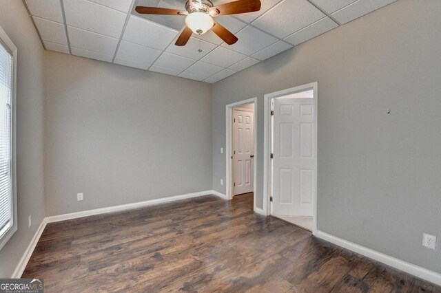 spare room with dark wood-style flooring, ceiling fan, a healthy amount of sunlight, and a paneled ceiling