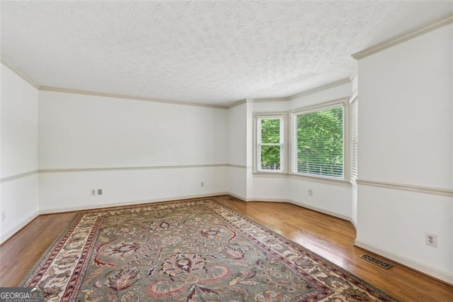 22 Oakwood Hills Dr, Suwanee, GA 30024 - empty room featuring visible vents, ornamental molding, wood finished floors, baseboards, and a textured ceiling