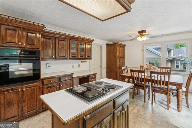 22 Oakwood Hills Dr, Suwanee, GA 30024 - kitchen with ceiling fan, stovetop with downdraft, black oven, a textured ceiling, and a center island