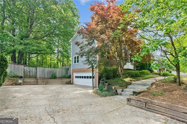 22 Oakwood Hills Dr, Suwanee, GA 30024 - view of property exterior featuring an attached garage, dirt driveway, and fence