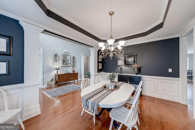 1738 Honey Tree Pl, Hoschton, GA 30548 - dining room with decorative columns, a decorative wall, wood finished floors, crown molding, and wainscoting