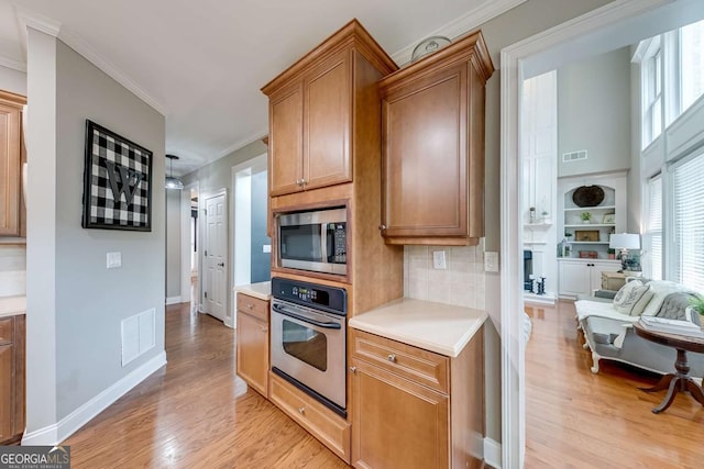 1738 Honey Tree Pl, Hoschton, GA 30548 - kitchen with stainless steel appliances, ornamental molding, light wood-style floors, light countertops, and tasteful backsplash