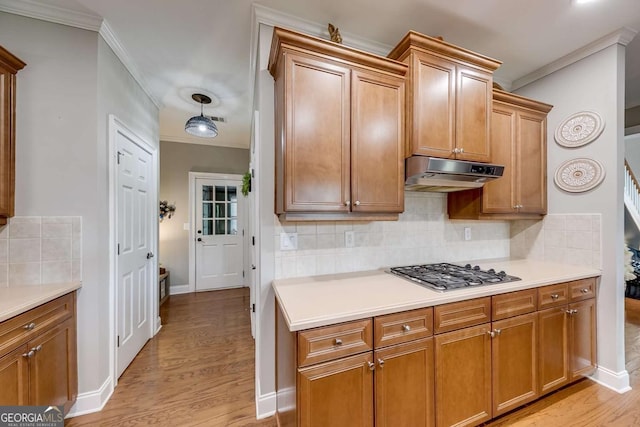 1738 Honey Tree Pl, Hoschton, GA 30548 - kitchen with stainless steel gas stovetop, under cabinet range hood, ornamental molding, light wood-type flooring, and tasteful backsplash