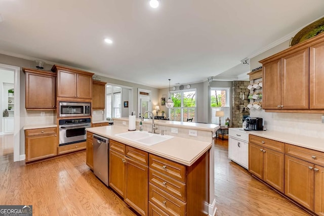 1738 Honey Tree Pl, Hoschton, GA 30548 - kitchen with appliances with stainless steel finishes, light countertops, light wood finished floors, a center island with sink, and decorative backsplash