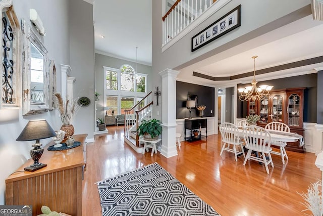 1738 Honey Tree Pl, Hoschton, GA 30548 - foyer entrance with a chandelier, wood finished floors, decorative columns, stairway, and ornamental molding
