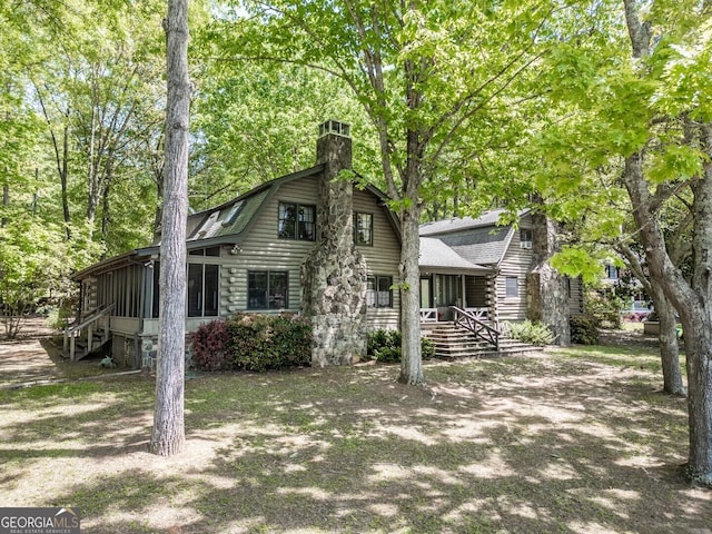 dutch colonial with log siding, a chimney, and a sunroom