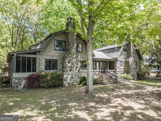 exterior space with log exterior, a chimney, a sunroom, and a gambrel roof
