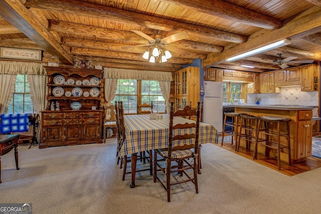dining area featuring wooden ceiling, beamed ceiling, a ceiling fan, and light carpet