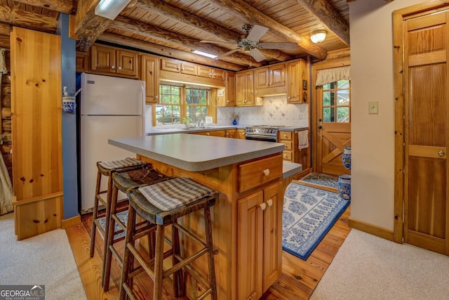 kitchen featuring stainless steel stove, freestanding refrigerator, a ceiling fan, wooden ceiling, and beamed ceiling
