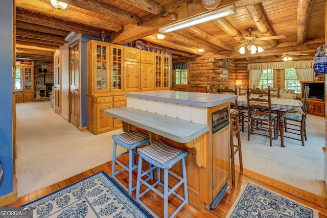 kitchen with wood ceiling, a kitchen island, a ceiling fan, beam ceiling, and rustic walls