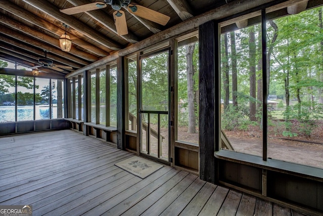 unfurnished sunroom featuring beamed ceiling, a water view, and ceiling fan