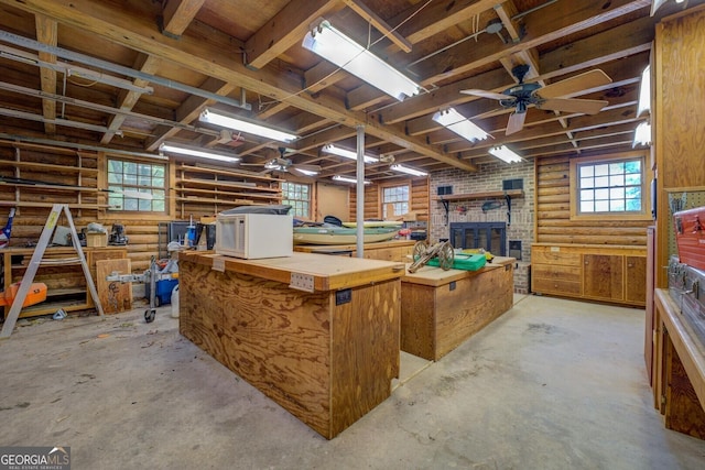 misc room with unfinished concrete floors, a workshop area, rustic walls, and a ceiling fan