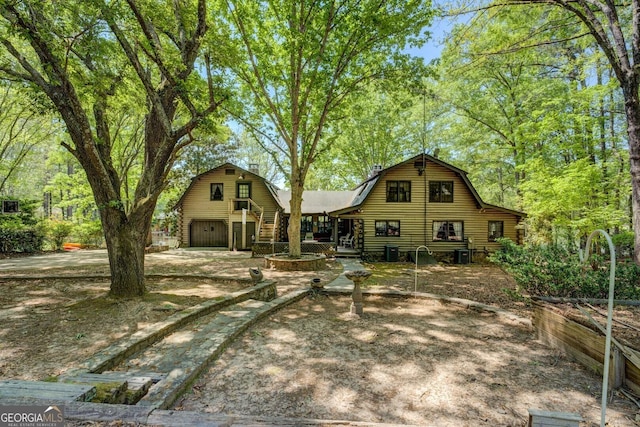 exterior space with a detached garage, a barn, log exterior, and a gambrel roof