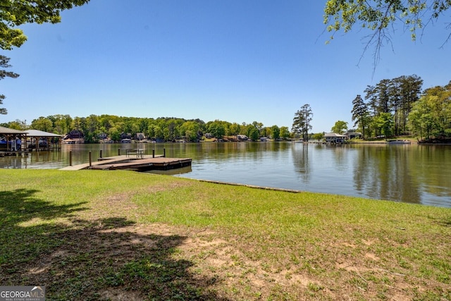 view of dock with a lawn and a water view