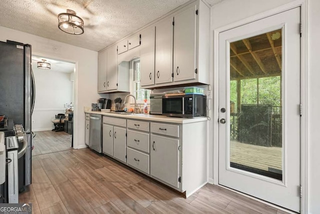 408 Walnut Dr, Woodstock, GA 30189 - kitchen with a sink, appliances with stainless steel finishes, light wood finished floors, light countertops, and a textured ceiling