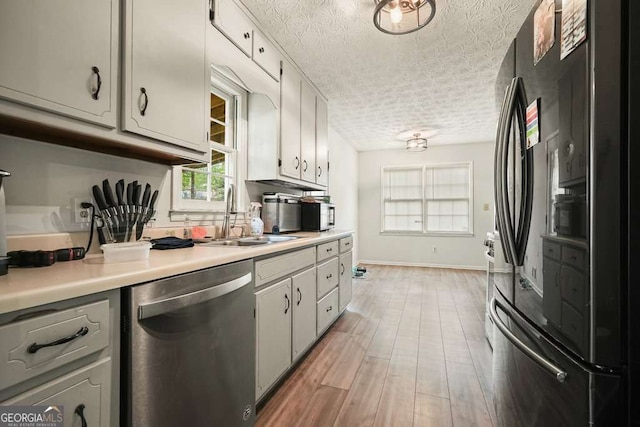 408 Walnut Dr, Woodstock, GA 30189 - kitchen featuring freestanding refrigerator, stainless steel dishwasher, a sink, a textured ceiling, and light countertops