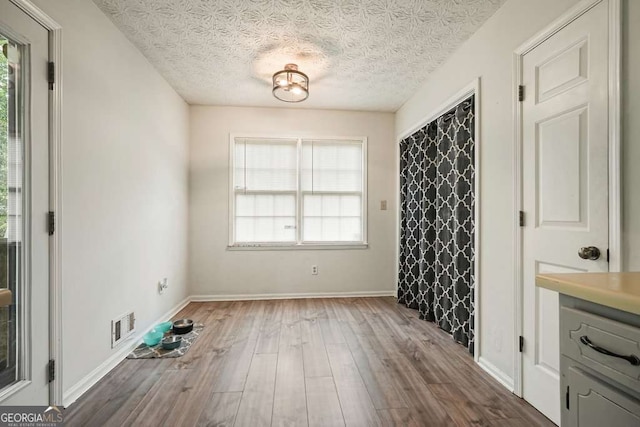 408 Walnut Dr, Woodstock, GA 30189 - unfurnished dining area with plenty of natural light, wood finished floors, a textured ceiling, and baseboards