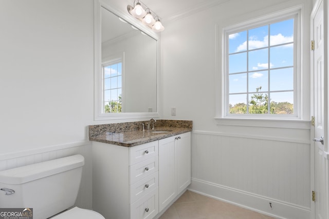 bathroom with plenty of natural light, wainscoting, ornamental molding, vanity, and toilet