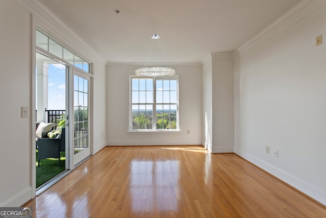 unfurnished room featuring a chandelier, ornamental molding, wood finished floors, and baseboards