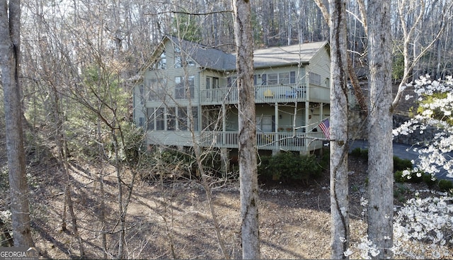 exterior space featuring roof with shingles, a wooded view, and a balcony