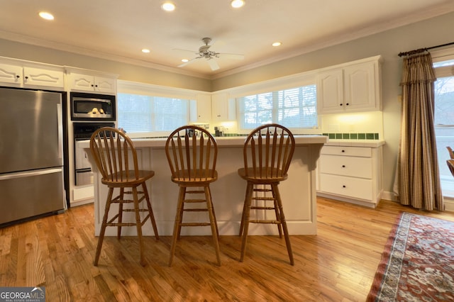 kitchen featuring white cabinetry, stainless steel appliances, crown molding, and a center island