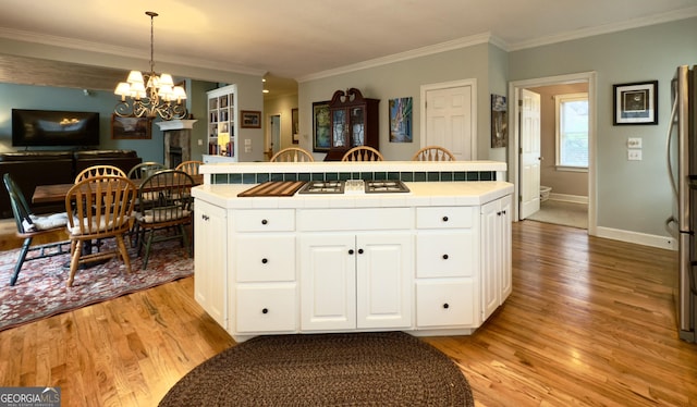 kitchen with crown molding, white cabinets, tile counters, a chandelier, and light wood-style floors