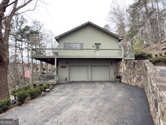 exterior space featuring a garage, a balcony, and aphalt driveway