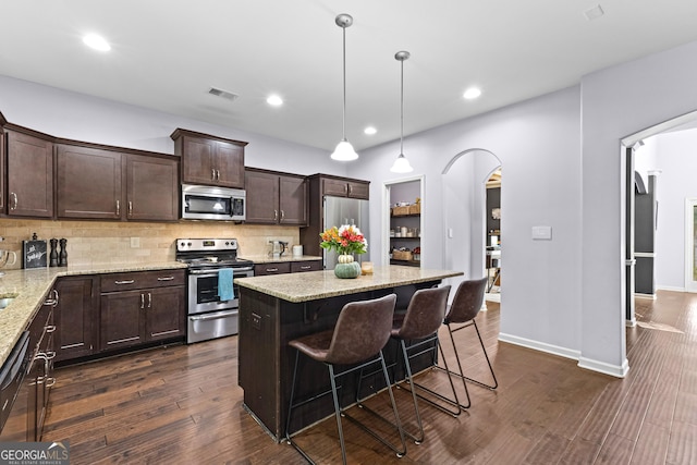 171 Cliffhaven Cir, Newnan, GA 30263 - kitchen with visible vents, appliances with stainless steel finishes, tasteful backsplash, arched walkways, and dark brown cabinets