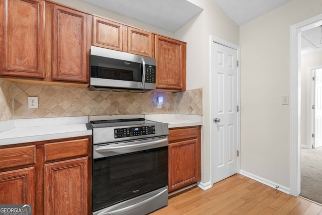 1452 Evanston Ln, Marietta, GA 30062 - kitchen with tasteful backsplash, appliances with stainless steel finishes, light countertops, light wood-type flooring, and brown cabinetry