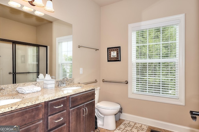 bathroom featuring baseboards, toilet, double vanity, and a sink
