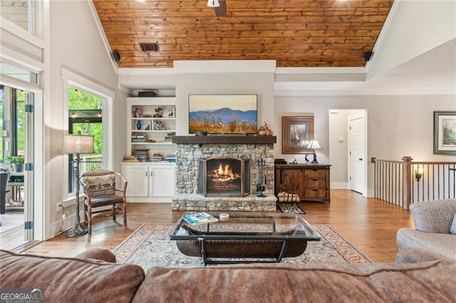 living room featuring wood ceiling, ornamental molding, wood finished floors, high vaulted ceiling, and a fireplace
