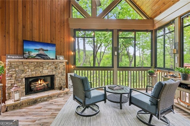 sunroom / solarium featuring a stone fireplace and lofted ceiling
