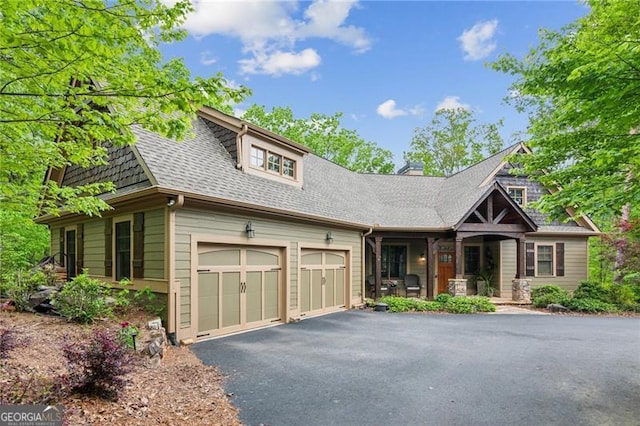 view of front of house with covered porch, a shingled roof, driveway, and an attached garage