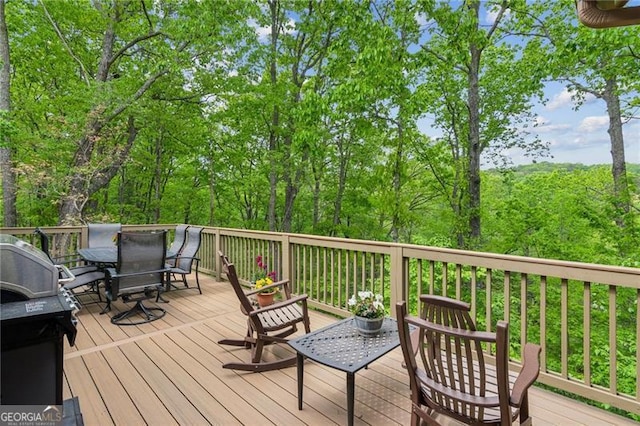 wooden terrace featuring outdoor dining space and a grill