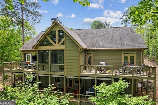 rear view of property with a deck, a chimney, and a shingled roof