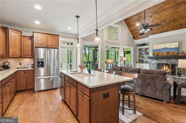 kitchen featuring stainless steel appliances, a sink, a kitchen bar, brown cabinets, and light wood finished floors