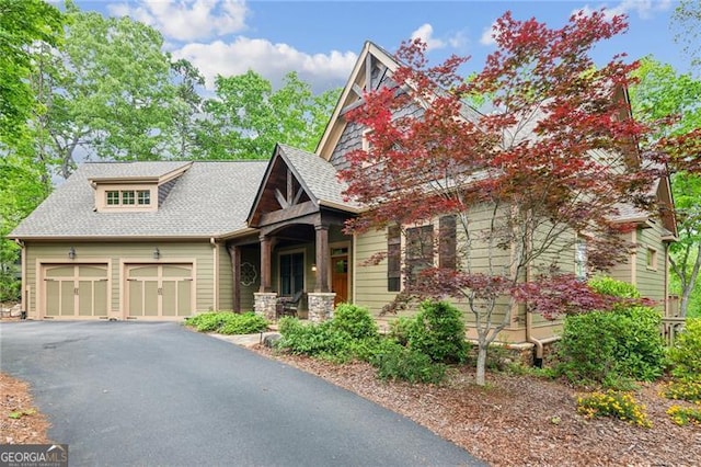craftsman house with driveway, an attached garage, covered porch, and a shingled roof