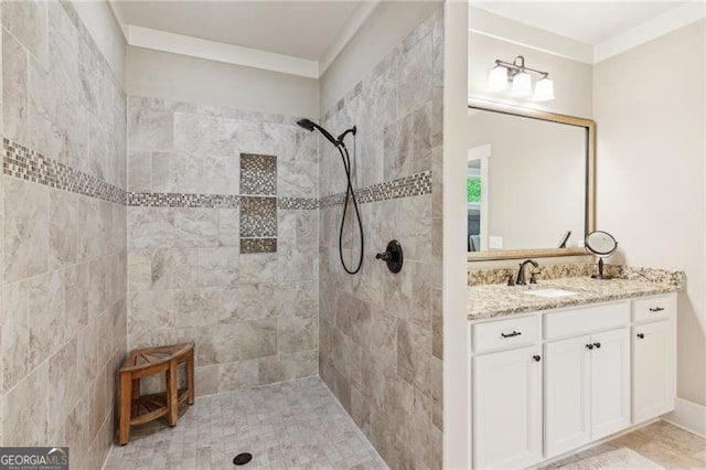 bathroom featuring a tile shower, vanity, and crown molding