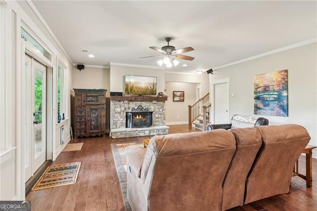 living room with crown molding, stairway, dark wood-type flooring, a fireplace, and ceiling fan