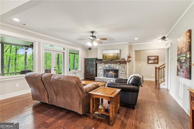 living room with ornamental molding, baseboards, a ceiling fan, hardwood / wood-style floors, and a fireplace