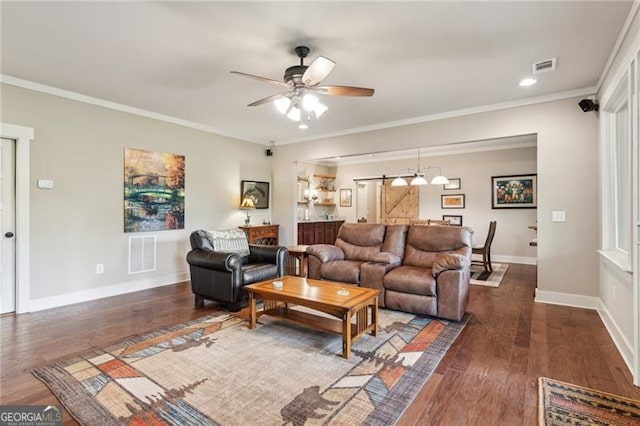 living room featuring ceiling fan, baseboards, wood finished floors, ornamental molding, and a barn door