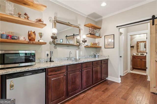 indoor wet bar with stainless steel microwave, a barn door, crown molding, dark wood-type flooring, and refrigerator