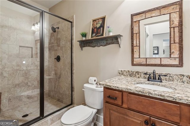 bathroom with a shower stall, toilet, and vanity