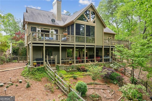 back of property featuring a deck, a chimney, and a sunroom