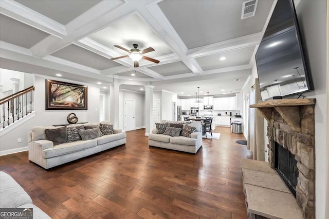 living area with dark wood finished floors, decorative columns, a ceiling fan, and beam ceiling