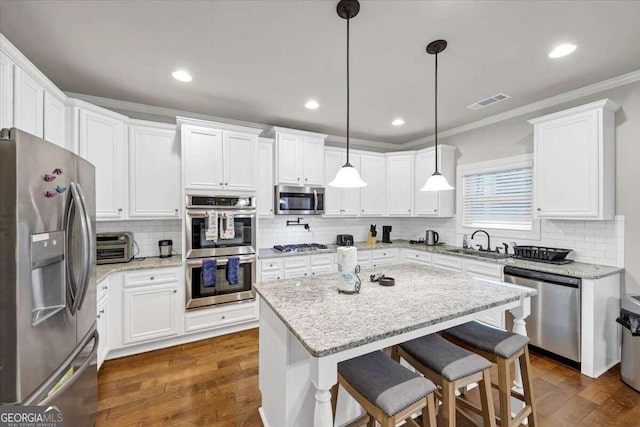 kitchen featuring ornamental molding, a sink, backsplash, and stainless steel appliances