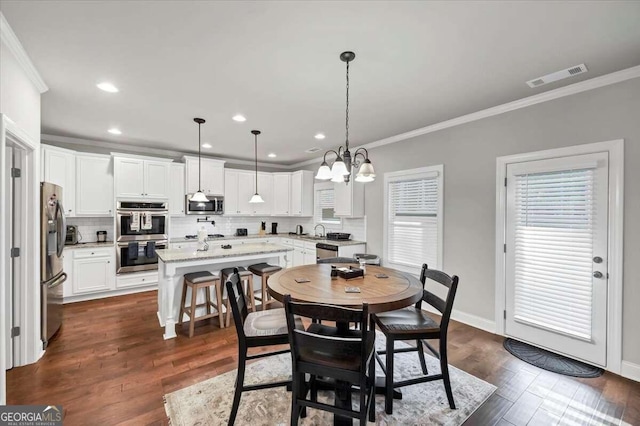 dining room featuring visible vents, baseboards, ornamental molding, dark wood finished floors, and a notable chandelier